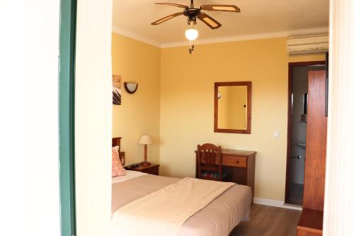 a bedroom with a bed and a dresser and a mirror at Costa Brava Alojamento in Benedita
