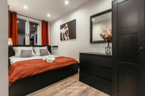 ein Schlafzimmer mit einem Bett mit einer Kommode und einem Spiegel in der Unterkunft Happy - Happy Apartamenty Mielec in Mielec