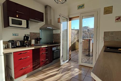 a kitchen with red cabinets and a balcony at Villa TILLA 110 m2, terrasse babyfoot fléchettes in Arcachon