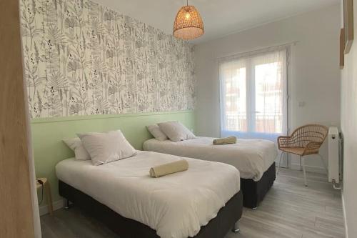 two beds in a room with a wall at Villa TILLA 110 m2, terrasse babyfoot fléchettes in Arcachon