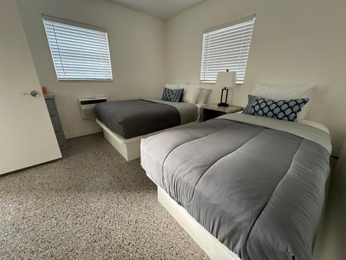 two beds in a room with two windows at EBBTIDE INN in St. Pete Beach