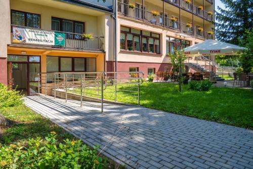 a building with a patio and an umbrella in front of it at Hotel Gromada Medical SPA Busko Zdrój in Busko-Zdrój