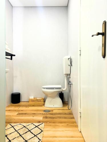 a bathroom with a toilet and a wooden floor at Costa Brava Alojamento in Benedita