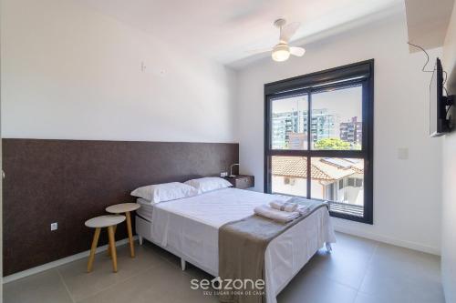 um quarto com uma cama e uma grande janela em Belo Estudio com design moderno CNT303 em Florianópolis