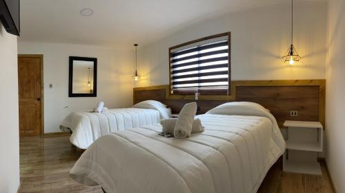 Habitación con 3 camas, sábanas blancas y ventana. en Residencial Victoria Said en Linares