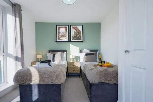 ミルトン・キーンズにあるStunning 4 Bedroom 2 Bathroom House - Close to City Centre - Sleeps 8 - Free Parking, Super-Fast Wifi and Smart TVs by Yoko Propertyの青い壁の部屋にベッドが2つある