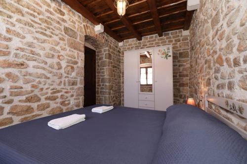1 dormitorio con 1 cama azul en una pared de piedra en House Cirrus, en Sukošan