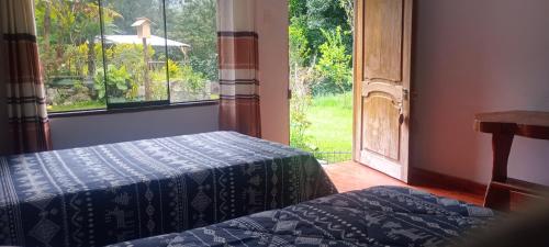 a bedroom with two beds and a large window at Lucmabamba Lodge in Santa Teresa