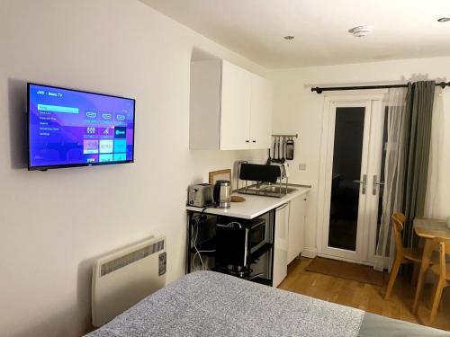 Habitación con cama y TV en la pared. en Garden studio in Bradford on Avon, en Bradford on Avon