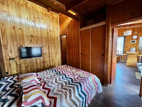 ein Schlafzimmer mit einem Bett in einem Holzzimmer in der Unterkunft Departamento E in Coihaique
