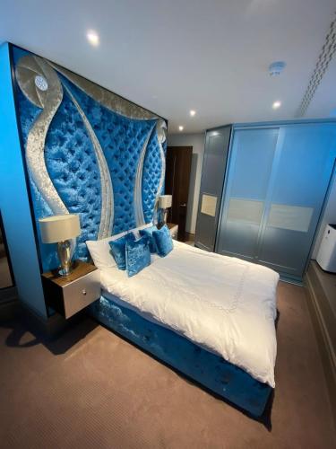 een slaapkamer met een groot bed met een blauw hoofdeinde bij Luxurious 2BD Flat Heart of London Mayfair! in Londen