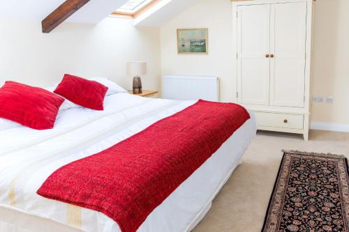 a bedroom with a large white bed with red pillows at Manor Coach House in Farrington Gurney