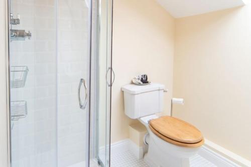 uma casa de banho com um WC e uma cabina de duche em vidro. em Manor Coach House em Farrington Gurney