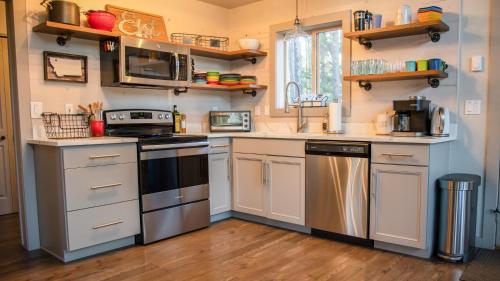 cocina con electrodomésticos de acero inoxidable y suelo de madera en Elk Street Retreat - Near Glacier Park en Columbia Falls