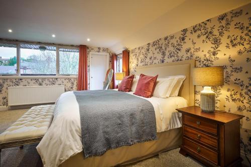 a bedroom with a bed and a table with a lamp at The Old Stables - Hot Tub, Sauna and Cinema in Alyth