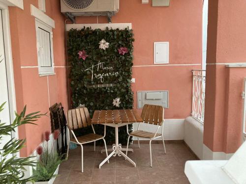 a table and chairs next to a wall with flowers at Maria Trafaria House in Trafaria