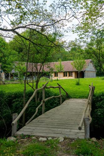 a wooden bridge with a house in the background at Chambres d hôtes du Moulin de Boiscorde in Rémalard en Perche