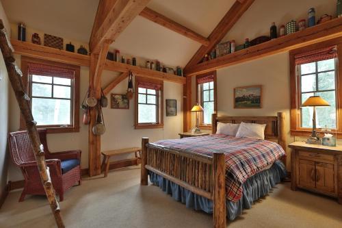 a bedroom with a bed and a chair and windows at Mountain Village Marvel with Hot Tub and Home Gym! in Telluride