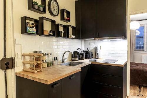 une cuisine avec un évier et une horloge murale dans l'établissement Montmartre superbe moderne appartement 4 personnes, à Paris