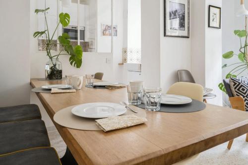 a wooden table with plates and glasses on it at Large house renovated in Paris - Welkeys in Paris