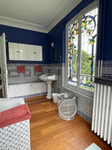 une salle de bains bleue avec lavabo et fenêtre. dans l'établissement Villa La Marquise de la Chesnaie à 15 mn de Paris, à Eaubonne