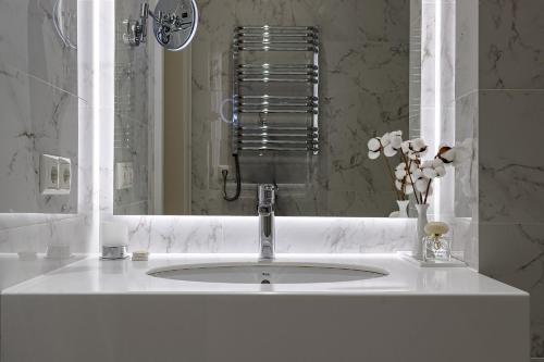 a white bathroom with a sink and a mirror at Modern Art Hotel in Lviv