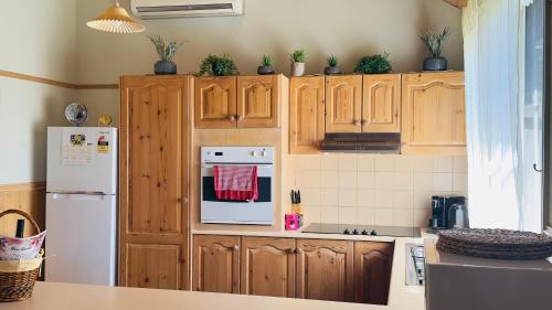 eine Küche mit Holzschränken und einem weißen Kühlschrank in der Unterkunft The Garden Cottage in Tawonga