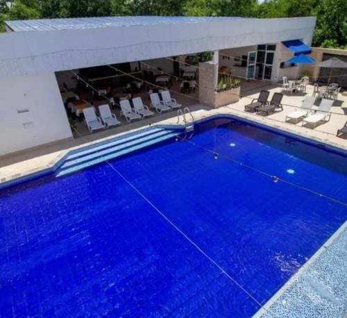 een groot blauw zwembad met stoelen bij hotel deluxe oasis de la colina in Girardot