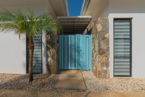 a blue fence in front of a house with a palm tree at Villas VR Beachwalk Avellanas in Playa Avellana