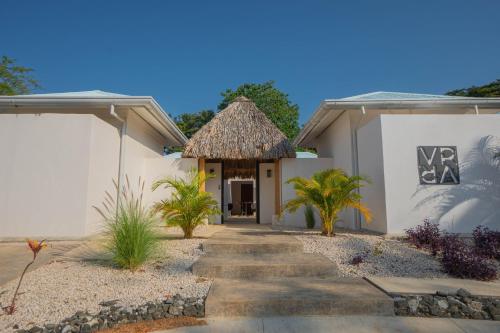 a house with a thatched roof and a pathway at Villas VR Beachwalk Avellanas in Playa Avellana