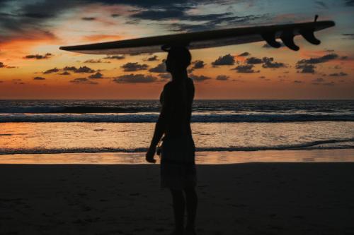 a man standing on the beach with a surfboard on his head at Villas VR Beachwalk Avellanas in Playa Avellana