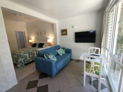 a living room with a blue couch and a bed at Muri Retreat Apartments in Rarotonga