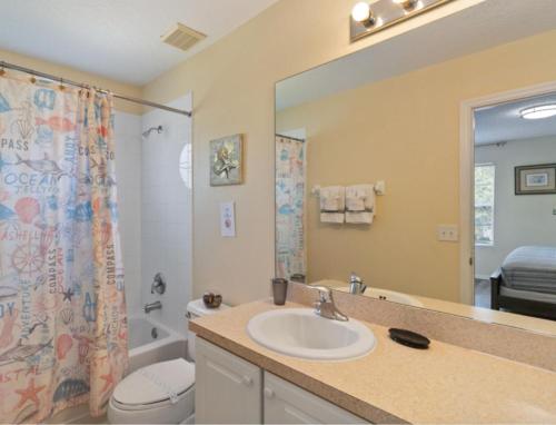 een badkamer met een wastafel, een toilet en een spiegel bij Emerald Island Resort, Private Pool, Game Room And Bbq Grill, Near Disney!! in Kissimmee