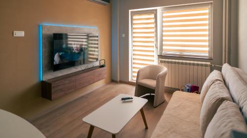 Una sala de estar con un sofá y un televisor. en Riverside Retreat, en Skopje