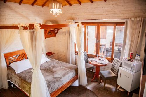 a bedroom with a bed and a table in a room at Chalés Cantinho do Sossego in Monte Verde