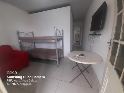 Apartamento em Muriqui - RJ - Apto. 202 في مانغاراتيبا: غرفة صغيرة مع طاولة وطاولة صغيرة وتلفزيون