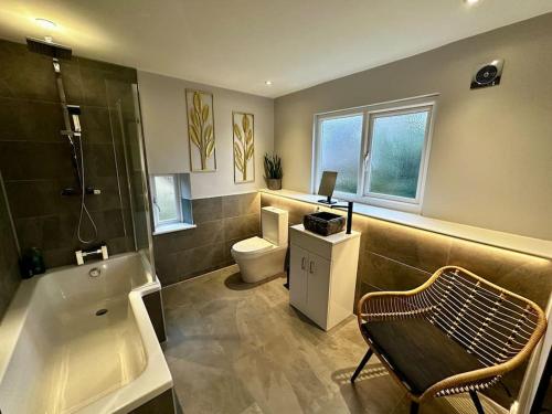 a bathroom with a toilet and a sink and a tub at Rustic stone cottage with Hot Tub & fireplace in Crowborough