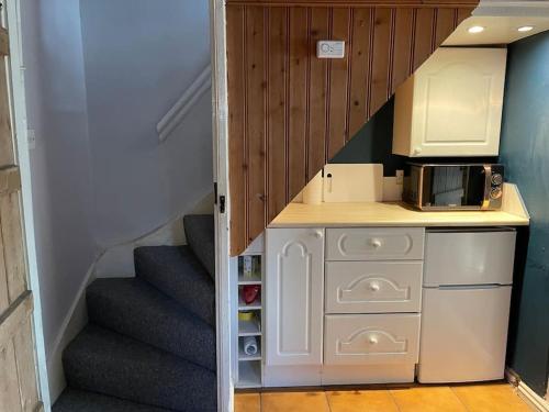 a small kitchen with a staircase with a microwave at Rustic stone cottage with Hot Tub & fireplace in Crowborough
