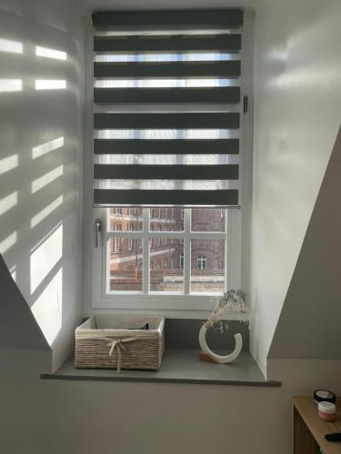 a window with a blinds in a room with a basket at Chambre privée Place aux oignons in Lille