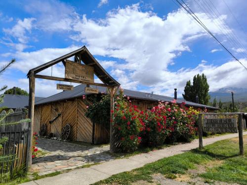 a sign in front of a building with flowers at Hotel Último Paraíso in Cochrane