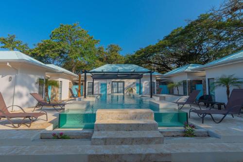een huis met een zwembad en enkele stoelen bij Villas VR Beachwalk Avellanas in Playa Avellana