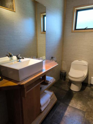a bathroom with a sink and a toilet and a mirror at Hotel Último Paraíso in Cochrane