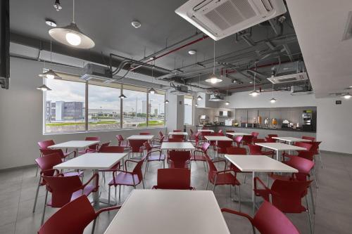 a restaurant with white tables and red chairs at City Express Junior by Marriott Guadalajara Periferico Sur in Guadalajara