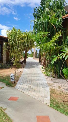 einen Backsteinsteg mit Pflanzen an der Seite eines Hauses in der Unterkunft Casa_Mare11 in São Miguel do Gostoso