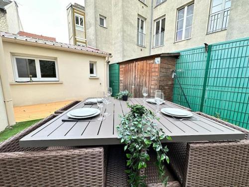 - une table en bois avec des assiettes et des verres à vin sur la terrasse dans l'établissement Landouzy maison centre ville, à Reims