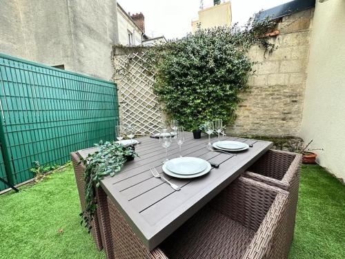 une table en bois avec des assiettes et des verres à vin dessus dans l'établissement Landouzy maison centre ville, à Reims
