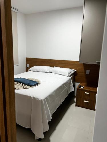 um quarto com uma cama branca e um espelho em Flat Pituba em Salvador
