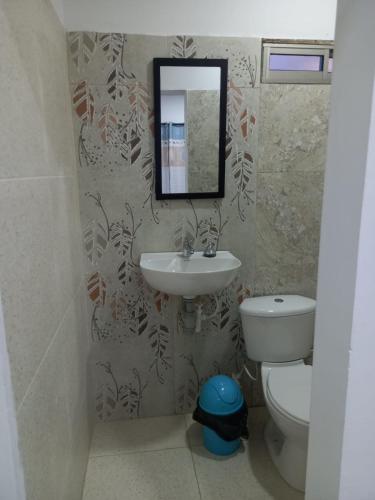 W łazience znajduje się umywalka, toaleta i lustro. w obiekcie Apartahotel Mar Azul w mieście Coveñas