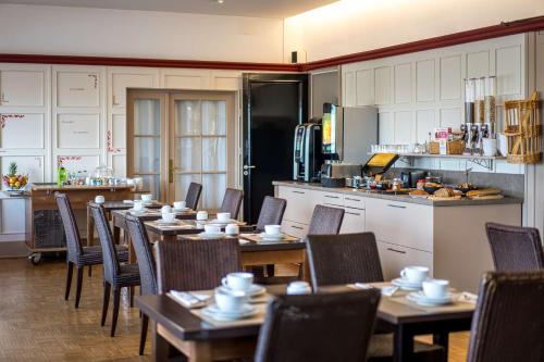 une salle à manger avec des tables et des chaises ainsi qu'une cuisine dans l'établissement Best Western Adagio Saumur, à Saumur