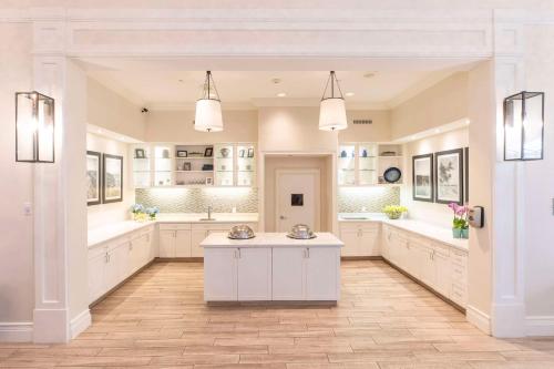 uma grande cozinha com armários brancos e uma mesa em Homewood Suites by Hilton Palm Beach Gardens em Palm Beach Gardens